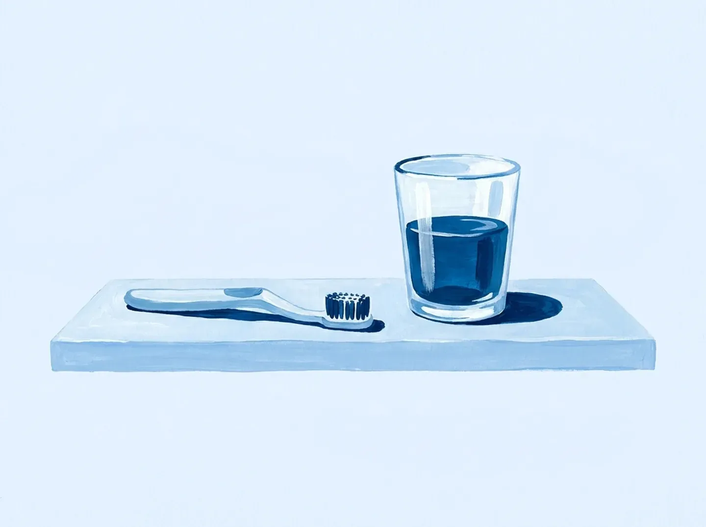 Un cepillo pequeño y un vaso de agua en la repisa del baño