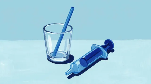 Un vaso pequeño con una pajita y, al lado, una jeringa dosificadora de las de farmacia