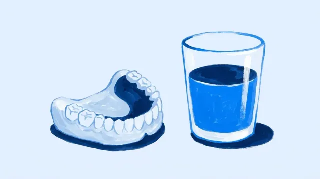 Una prótesis removible sobre la mesa junto a un vaso de agua