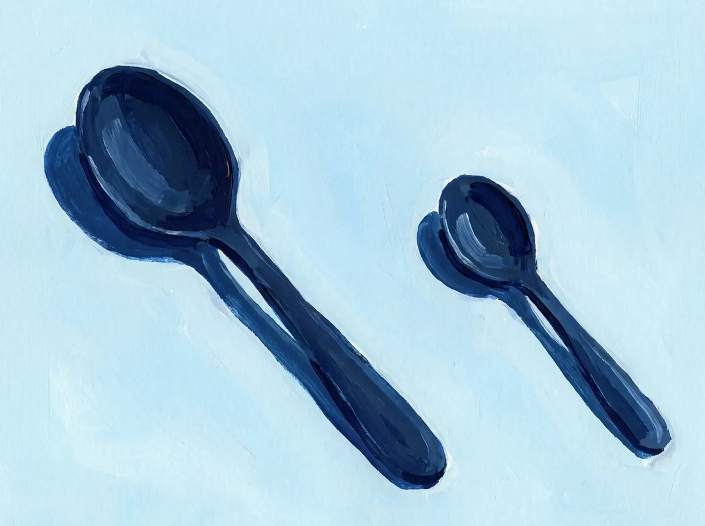 Dos cucharas separadas sobre la mesa, una grande y una pequeña