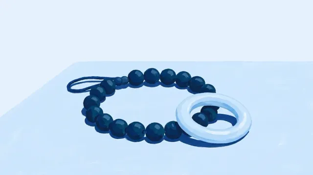 Un collar de cuentas y un mordedor de silicona, uno junto al otro sobre la mesa
