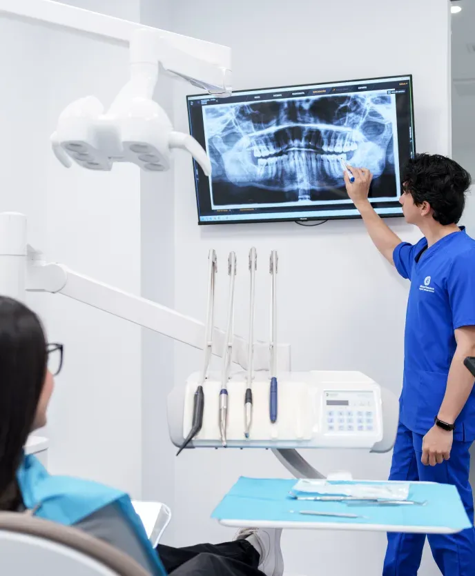 Un dentista de Cleardent señala en la pantalla la radiografía de una paciente mientras se la explica