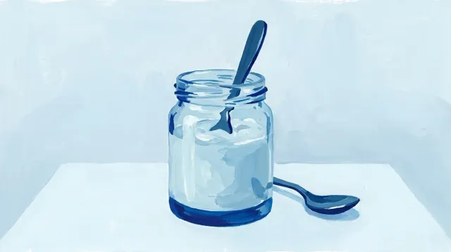 Un vaso con líquido espeso y una cuchara apoyada al lado, que se sostiene sola