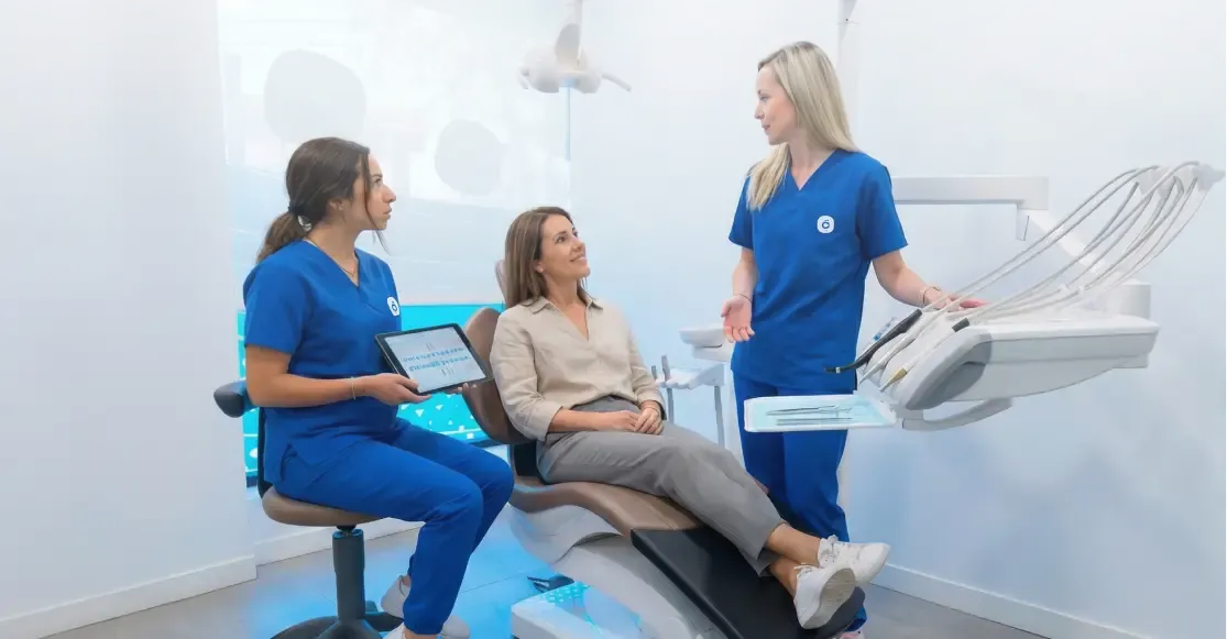 Dos profesionales de Cleardent conversan con una paciente sentada en el sillón