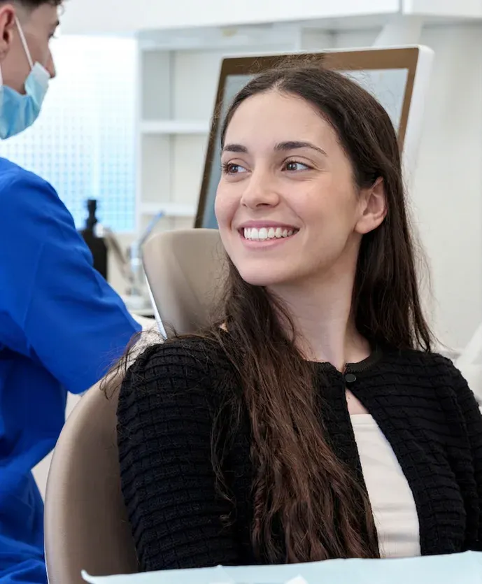 Una paciente sonríe sentada en el sillón del dentista