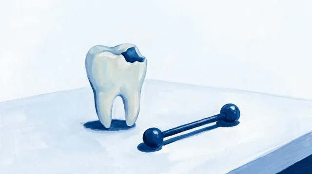 Un piercing de barra con sus dos bolas y, al lado, un diente con una muesca en el borde