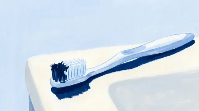 Un cepillo de dientes sobre el lavabo con la punta de las cerdas manchada